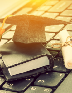 photo of grad cap, textbook and diploma on top of a computer keyboard
