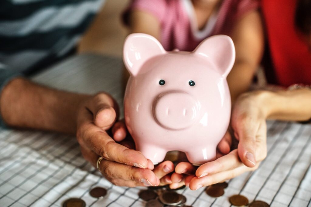 family of three holding a porcelain piggy bank