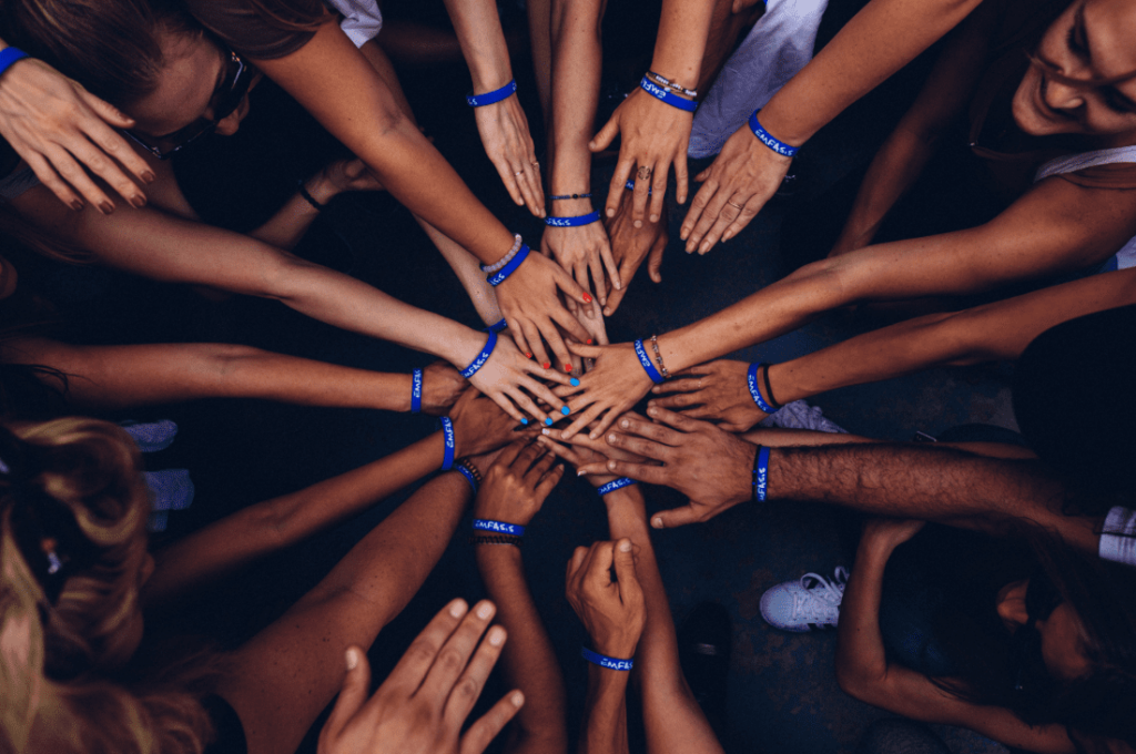 aerial view of blue bracelets on individuals performing a team hand stack