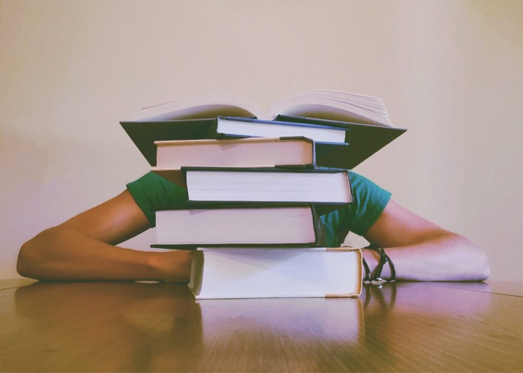 a person with head down behind a stack of books