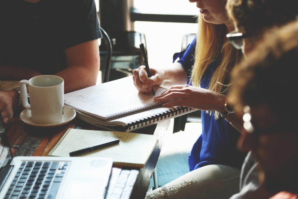 students gathered around coffee cup at a desk taking notes