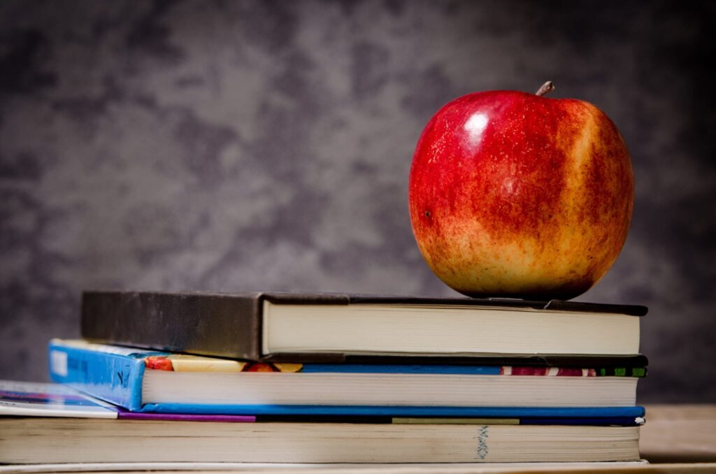 an apple on top of three stacked books