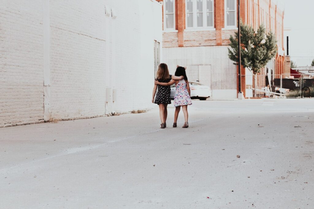 two women embracing as they walk down an alley