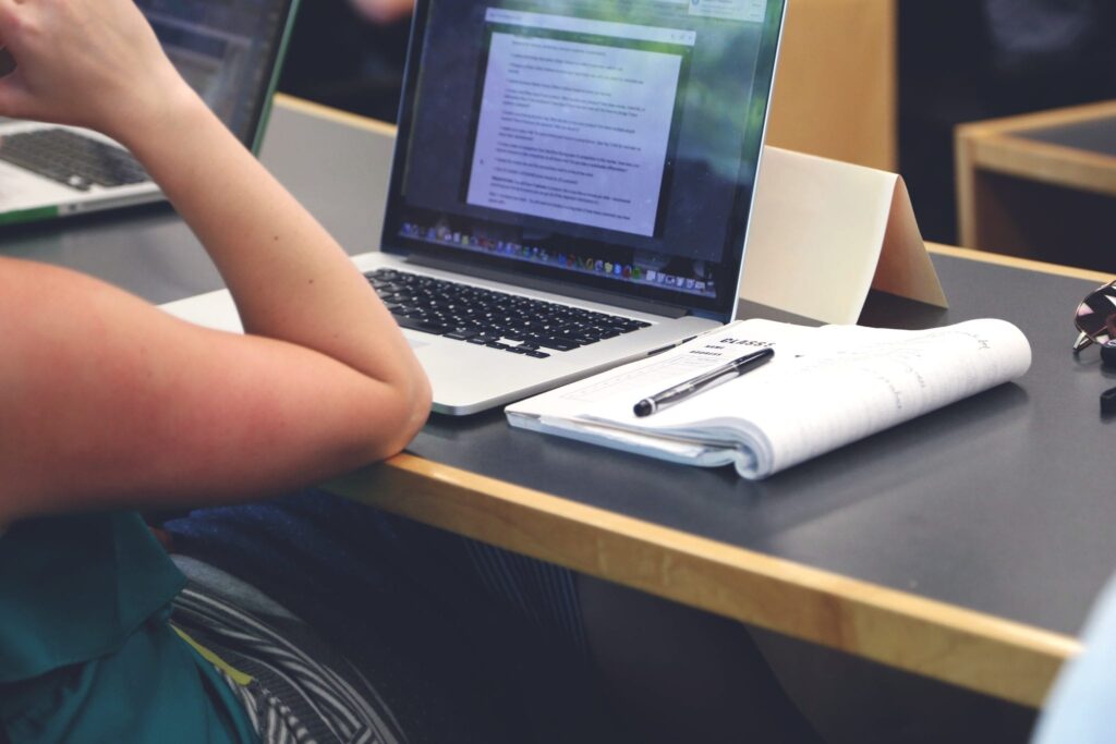 student in class sitting with a laptop and notebook