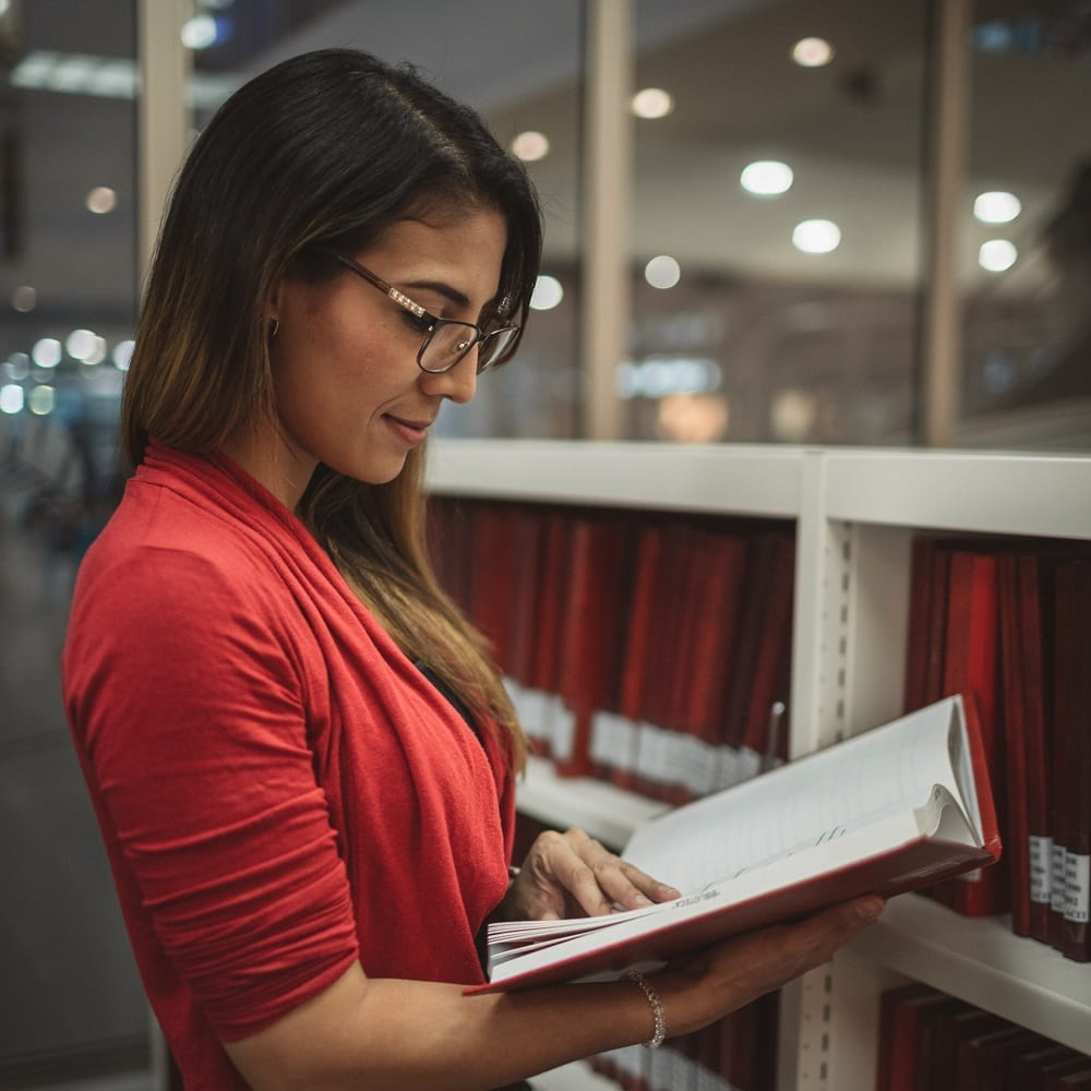 student reading research papers at a college library