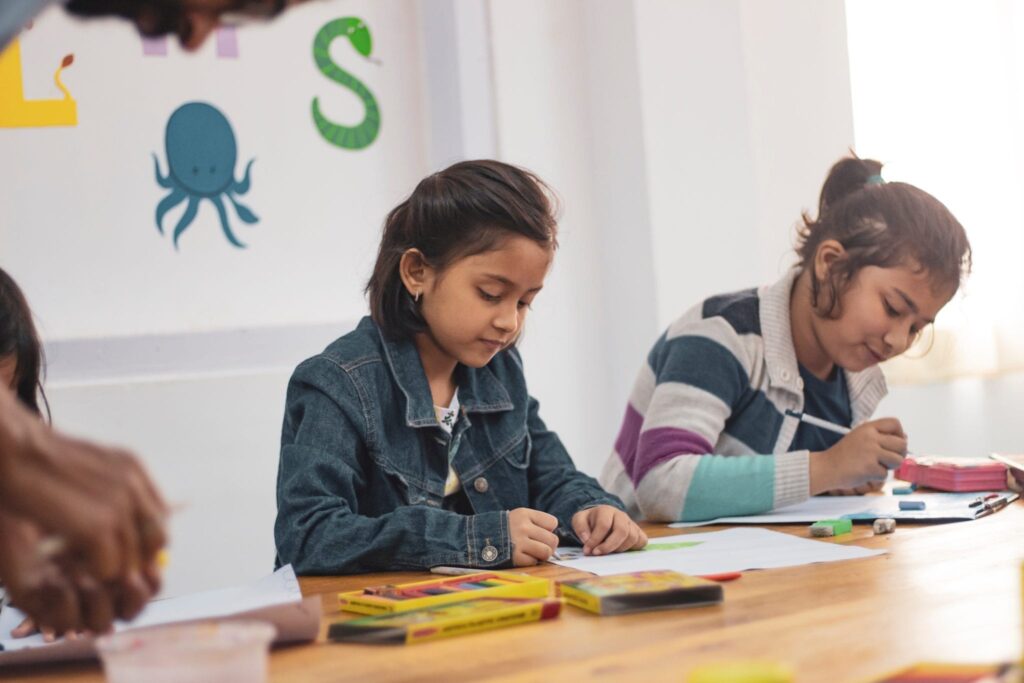 grade school children at a table drawing and coloring