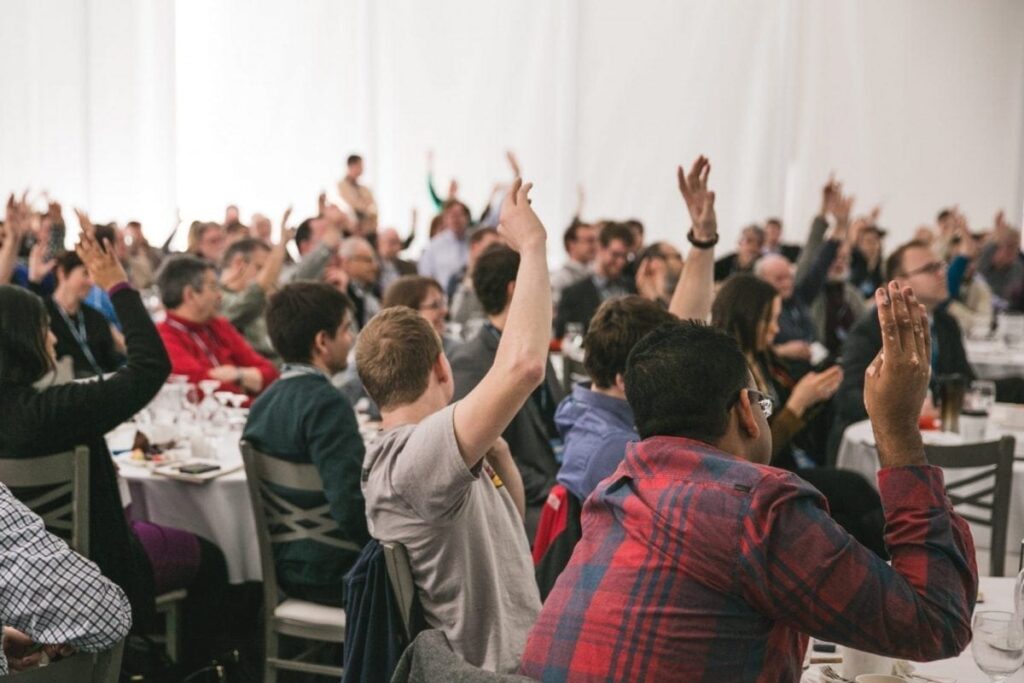 Student Voice crowd participating with raised hands at event