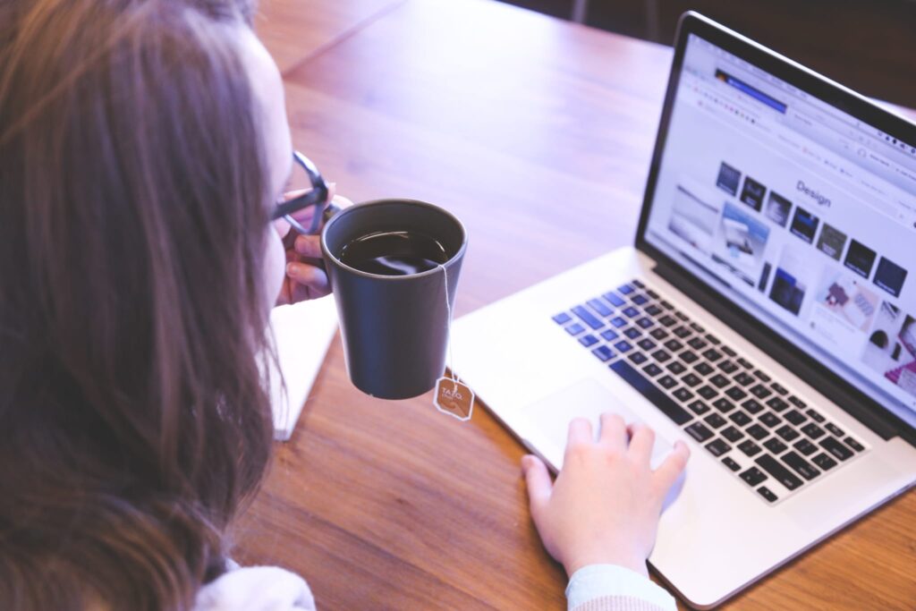 person drinking tea while working on a laptop