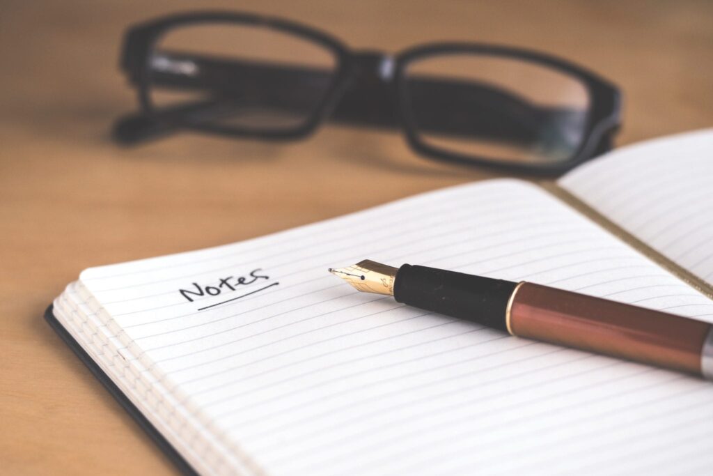 Pen on top of Note pad on the desk with glasses