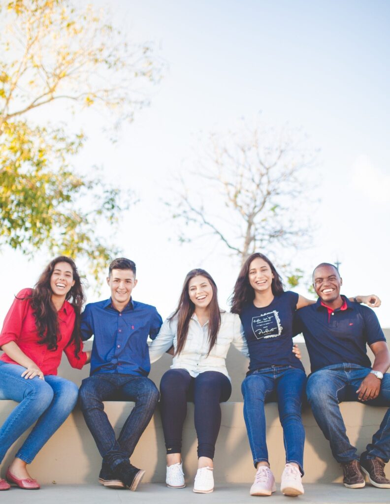 four students pose happily together on a bench outdoors.