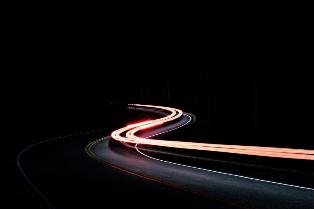 Time-lapsed photo of car driving down curvy road at night