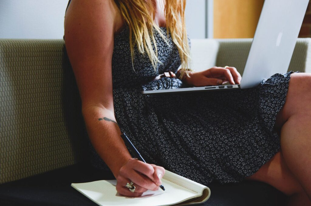 woman in a dress with laptop taking notes