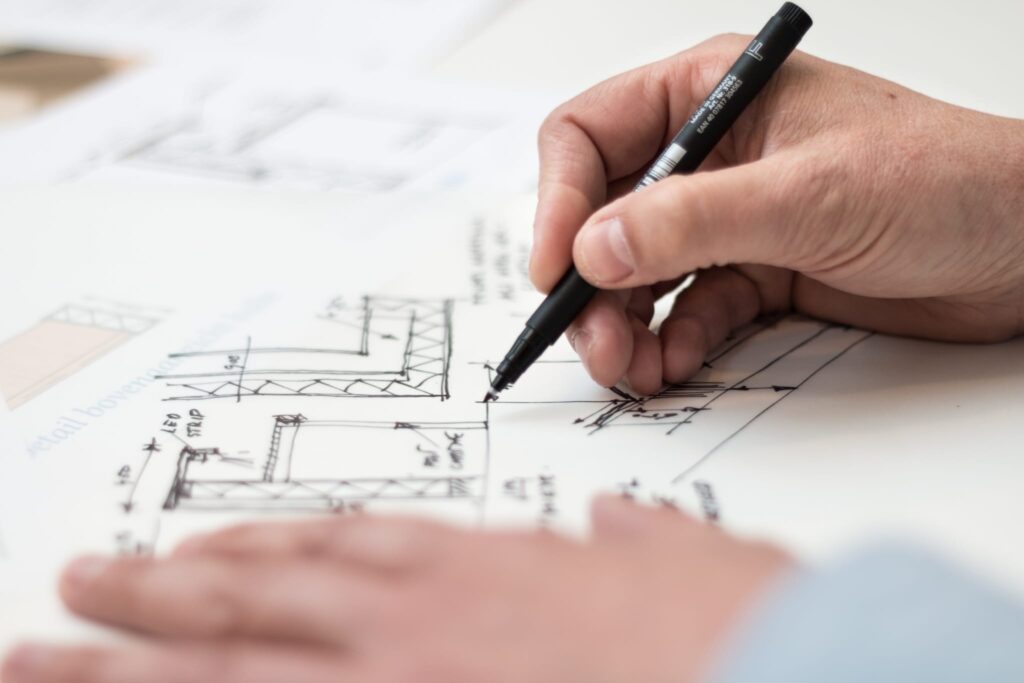 hand holding black pen sketching floorplans