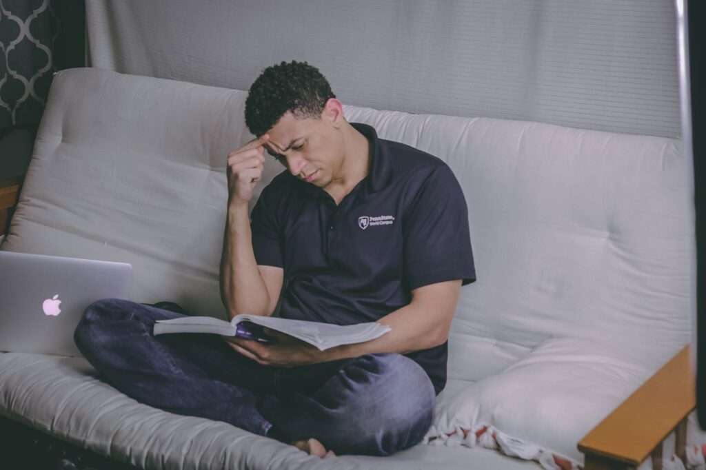 man on futon reading from textbook