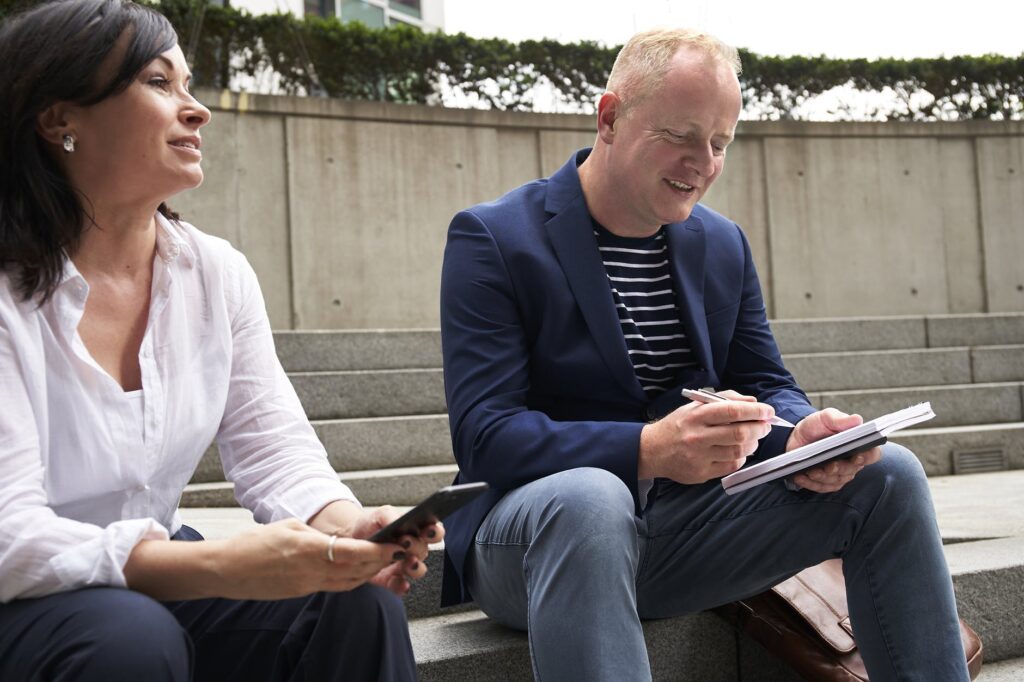 two people taking and taking notes outside