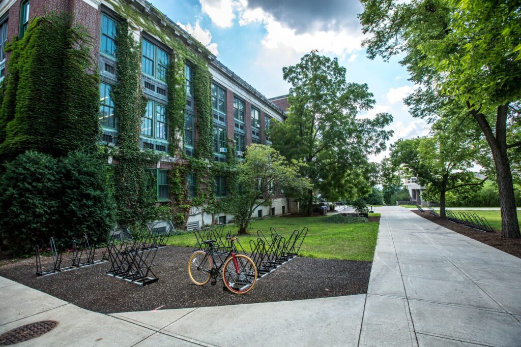 single bike in a bike rack in front of an ivy-covered school