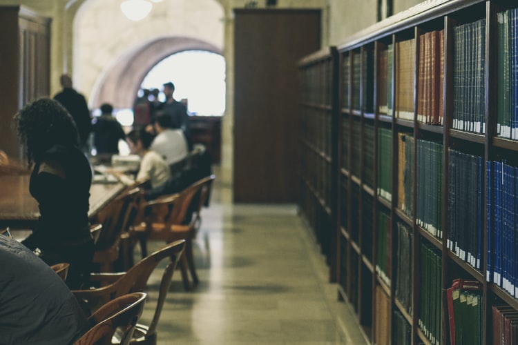 stack of books with people studying in library